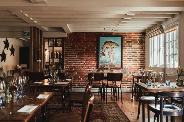 The restaurant at the tickled trout, with exposed brick, dark wooden tables and a large red rug