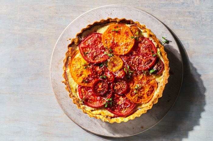 A tomato tart on a round plate with a grey wood background