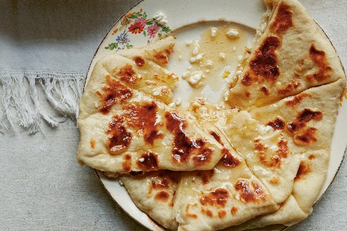 Round flatbread cut into triangles on a white plate