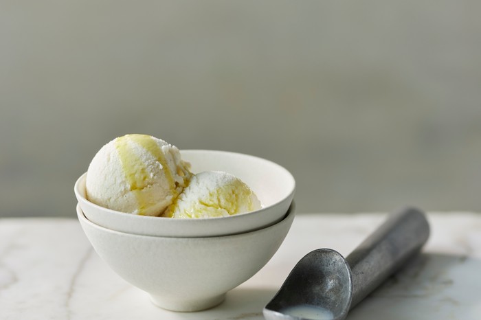 A bowl of ice cream with a scoop on the side