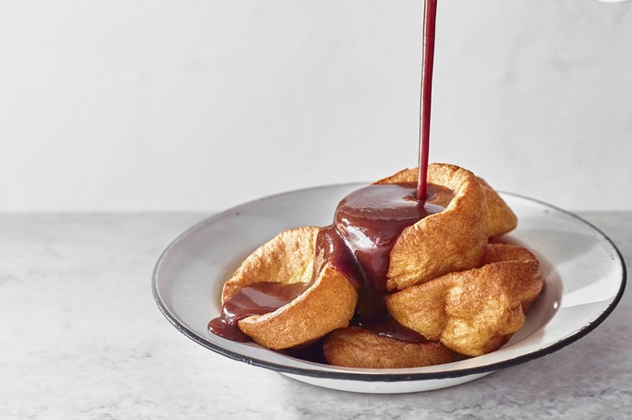 A plate of Yorkshire pudding with gravy being poured over