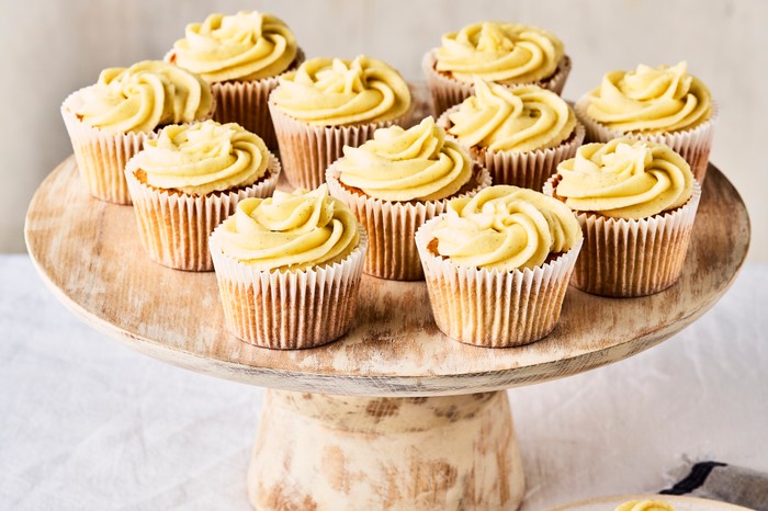 A cake stand full of cupcakes with creamy piped frosting on a white linen table cloth