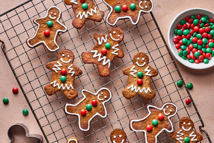 A batch of vegan gingerbread men decorated with buttons and icing, resting on a cooling rack