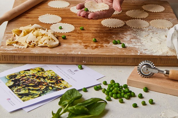 A wooden board with fresh pasta being rolled out and cut into shapes