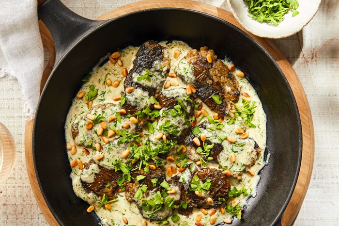 A pan of stuffed vine leaves with toasted nuts on the side