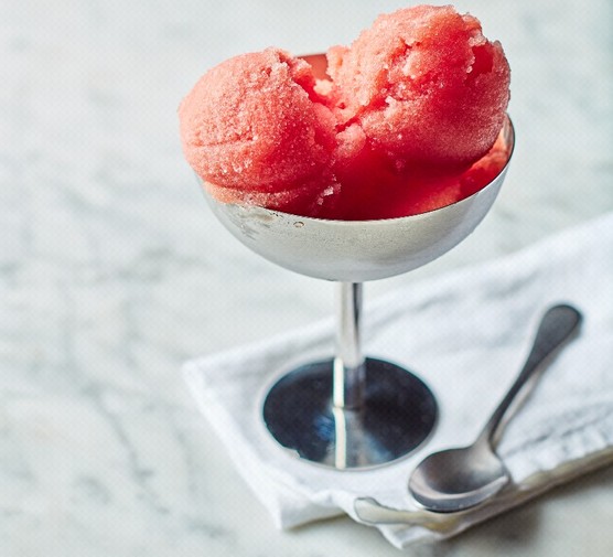 A silver dessert cup filled with scoops of red sorbet on a white napkin