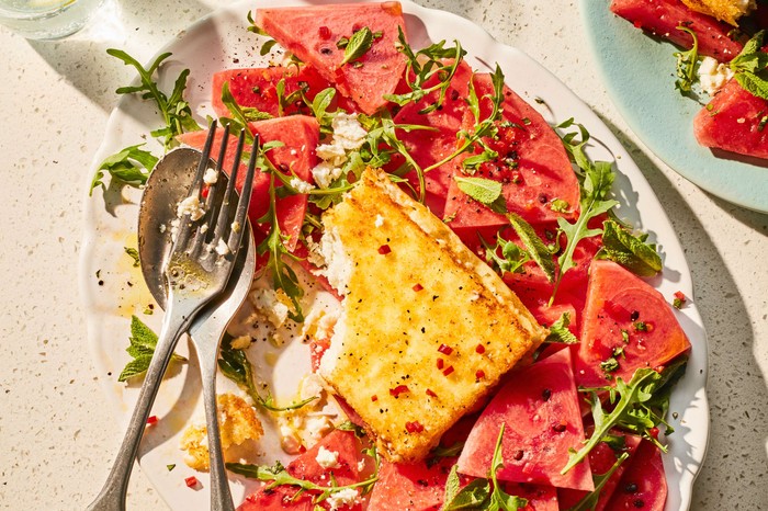 Baked feta surrounded by watermelon slices on a large platter