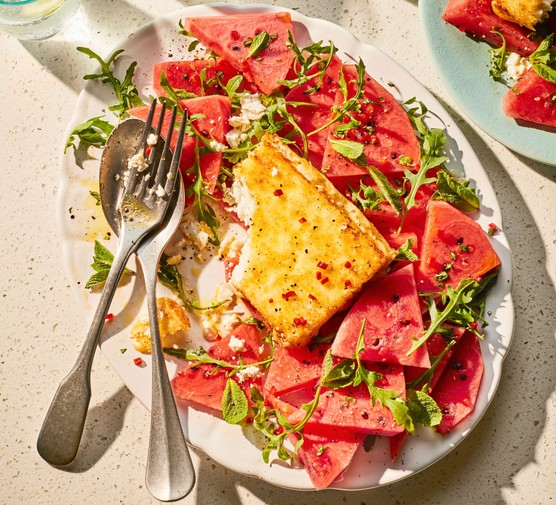 Baked feta surrounded by watermelon slices on a large platter