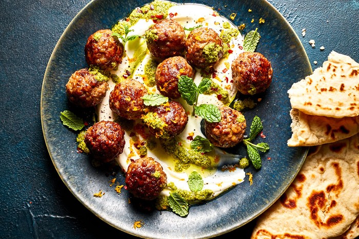 Plate of meatballs in a sauce next to flatbreads