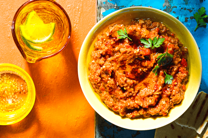 BBQ aubergine and pepper dip in a bowl with a blue and orange background