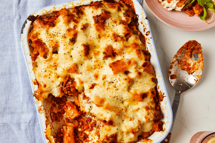 Bolognese pasta bake topped with cheese in a baking dish