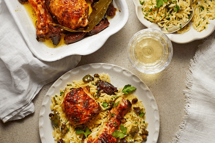 Chicken marbella on a bed of rice with a glass next to it