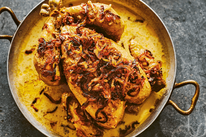 Whole roast chicken in a turmeric sauce with fried onions on top