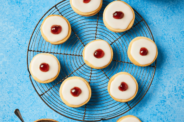 Empire biscuits with jam in the middle and icing on a wire rack