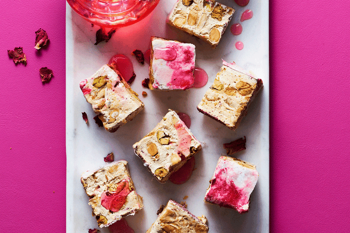 Squares of rose ripple and lemon nougat on a board with a pink background