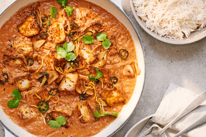 Halloumi curry in a big bowl with a bowl of fluffy white rice on the side