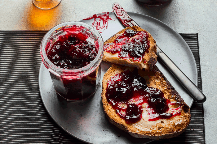 Jar of homemade cherry jam in a jar next to toast