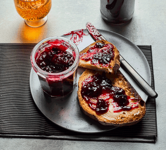 Jar of homemade cherry jam in a jar next to toast