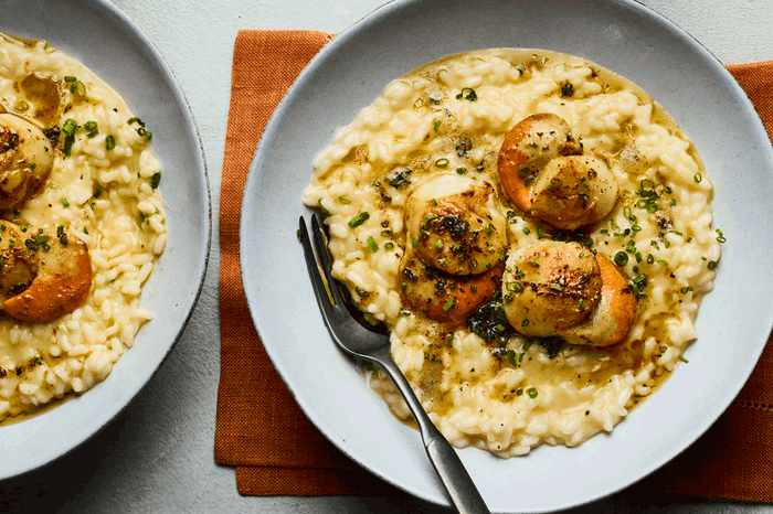 Two bowls of creamy risotto topped with scallops