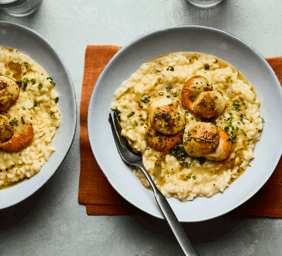 Two bowls of creamy risotto topped with scallops