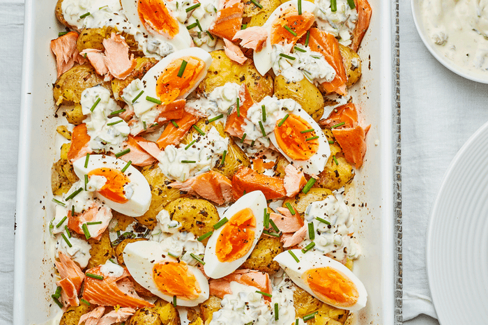 Hot smoked salmon hash in a roasting tin with hard boiled eggs and garnished with dill