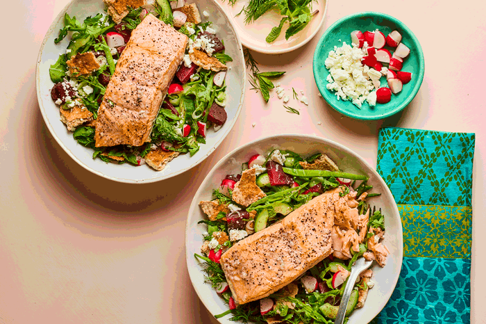 Two bowls of fattoush topped with salmon fillets