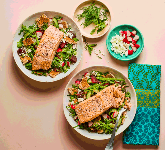 Two bowls of fattoush topped with salmon fillets